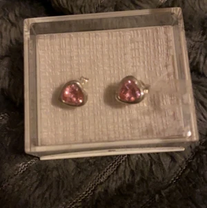 Oanvända örhängen - Supergulliga hjärtformade örhängen. Förpackningen är lite smutsig då den legat i en låda i flera år där jag haft pyssel. Örhängena har legat säkert inuti paketet :) Aldrig använt då jag inte har hål i öronen. Jag vet dock inte vad det är för material ❤️