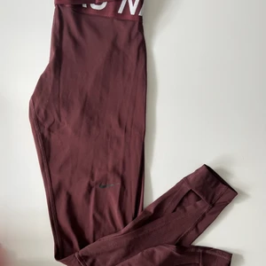 Nike Träningstights  - Träningstights i nyskick! Vinröd i färgen och har snygga detaljer längst ner i benen. Storlek S. 