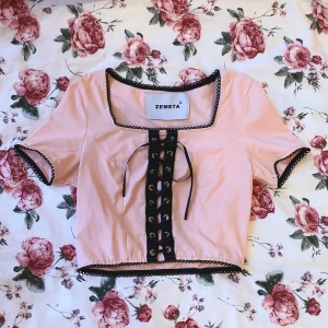 rosa tröja - Rosa tröja med svarta detaljer och snörning. har lite smuts på baksidan men inget som märks och går säkert att få bort. den är inte genomskinlig utan bra kvalitet och sitter väldigt fint!