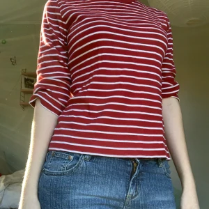 Röd och vit randig tröja - En röd och vitrandig tröja med trekvartsarmar. Väldigt sjön och annvänd många gånger. Den är i storlek L men skulle säga att den passar S och M också.