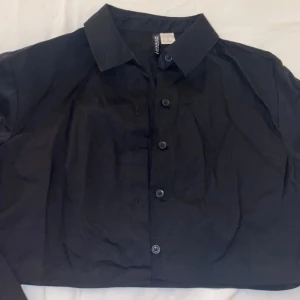 Kroppad svart skjorta från H&m  - En väldigt fin oanvänd kroppad skjorta🥰har storlek xxs men passar som ett xs också. Om man gillar korta skjortor passar den som ett s också. 
