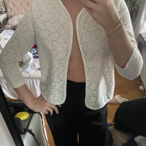 Vit kofta från Jacqueline de Yong strlk L - En lyxig vit kofta med ett blommigt mönster. Går att använda både med ett linne under eller fästa en säkerhetsnål och bära den som topp (se bild). Passar en S och M också! Aldrig använd, nyskick!