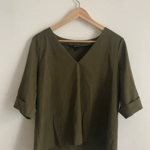 Kakigrön topp från Mobki Stl XS-S - Kakigrön v-ringad topp från Monki med vikta detaljer på ärmarna. Stl XS men sitter inte tight på mig som är S/M. Sparsamt använt. 