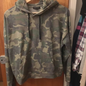 Hoodie - Camouflage färgad hoodie i tunt men varmt material. Väldigt skön att ha på sig då den känns mjuk på insidan. Inte lika lång som vanliga hoodies men den går till midjan eller kanske lite över beroende på hur lång man är🥰