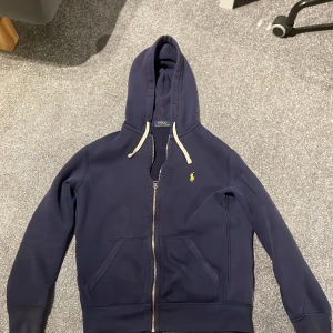 Ralph Lauren zip up - En nice zip up som jag har växt ur. Den är använd men har inga tydliga tecken på slitage. Det ändå skulle vara att färgen på ziphuvudet har lossnat lite( bild 3). Skriv för fler bilder eller om du har någon fråga.