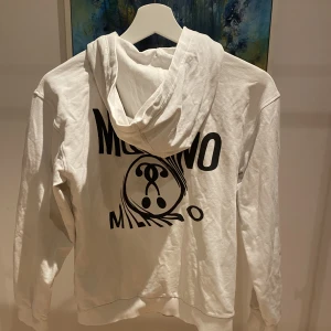 Moschino zip hoodie - En Moschino zip hoodie i storlek Xs. Nypris på denna ligger omkring 1000 kr. Den har inte några skador utan bara använd ett fåtal gånger. Skicket är 9/10. Den är självklart äkta.  Den finns fortfarande kvar.