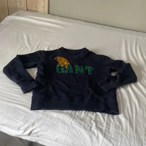 Gant  - En mörkblå gant tröja, använd 1-2 gånger, stort gant märke i mitten med en tiger på med. Väldigt bra skick 