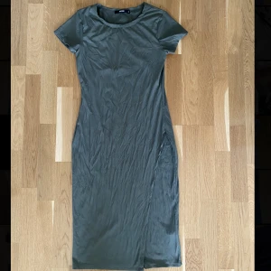 Grön Klänning i Stretch  - Superskön vadlång ribbad klänning i stretch som även har en liten slits längs med ena benet💕Kommer tyvärr inte till användning, inga fläckar😊