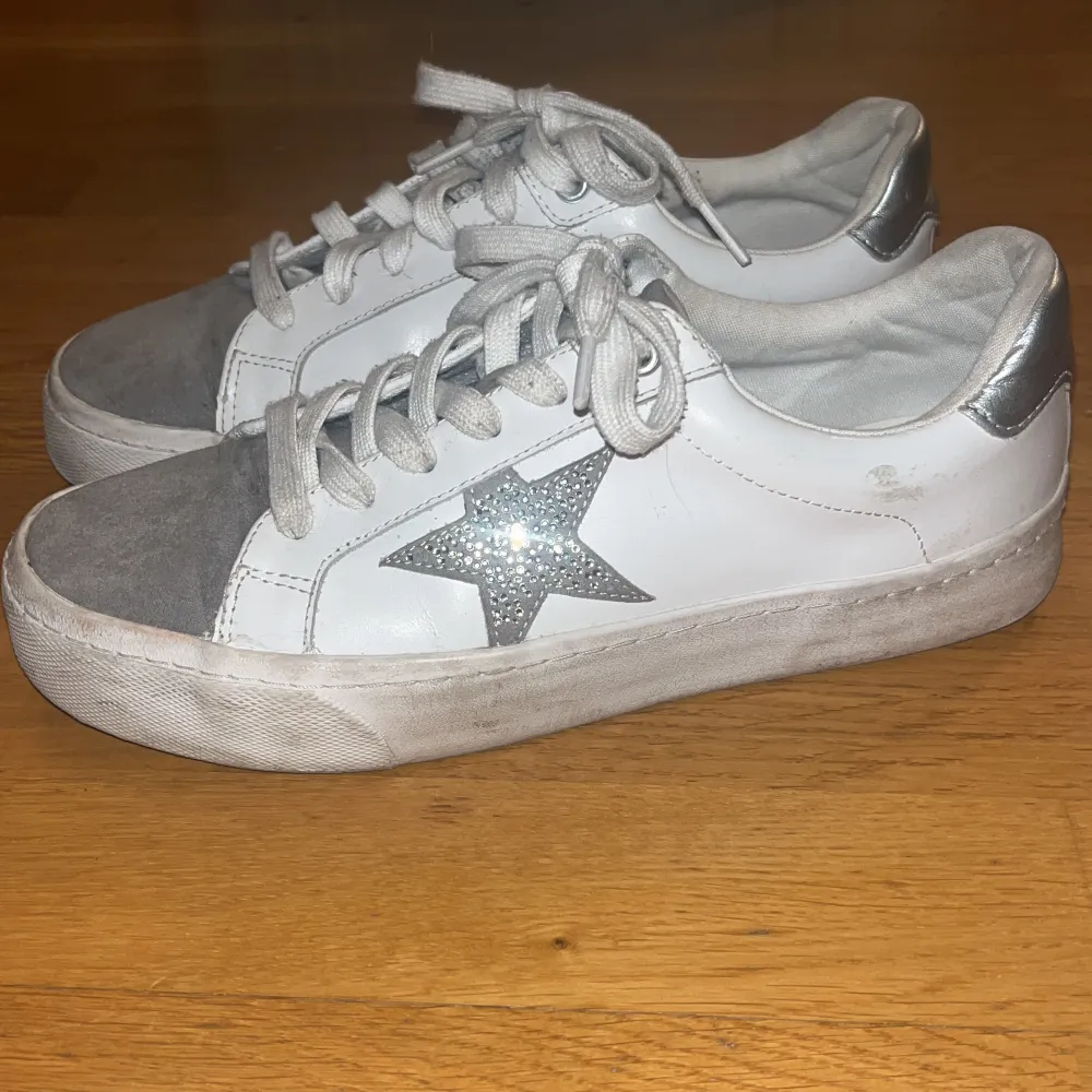 Ett par grå vita sneakers med stjärna på.⭐️Köptes för 660kr på Zalando. Storlek 41 men sitter mer som 40.😊. Skor.