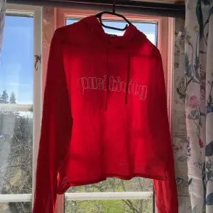 Tunn hoodie i en klar röd färg med en vit text som säger positivity