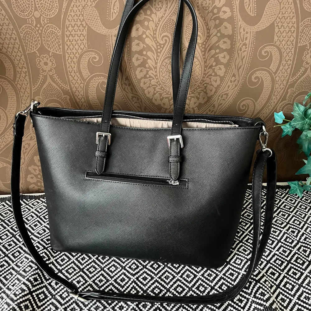 En svart ganska basic handväska, bra skick👍🏻 Axelband och vanliga ”handtag”, 3 fickor invändigt och en på baksida. . Väskor.