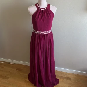 Bröllopsklänning i rosa/lila  - En superfin klänning finklänning som man kan ha på bal, bröllop, fester och så vidare. Man kan justera banden i ryggen på olika sätt. Den är bara använd vid ett tillfälle som var ett bröllop! Köpt för 900kr!! St UK12 alltså M!!