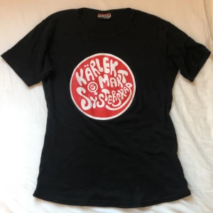 T shirt med tryck -  har sytt på en svart tygbit på ena ärmen då det är ett tryck där. Det stora trycket är lite sprucket annars i fint skick. Går att ta bort tygbiten lätt om det stör men tycker själv inte att det märks! Står L men tycker själv det är en S