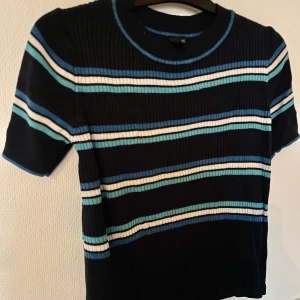 Ribbad topp - En snygg, ribbad, blårandig topp. Knappt intill använd, superfin och lätt att matcha med! Toppen är i tjockare tyg och har storleken M. 