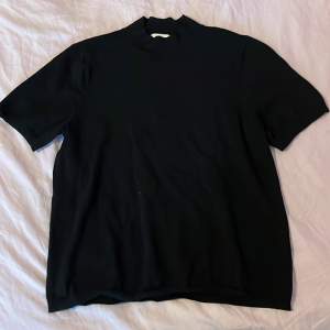 En svart stickad t-shirt med lite högre krage och lite längre ärmar, från H&M Basics i strl L. Basic men väldigt fin till ett par jeans eller vad som. 