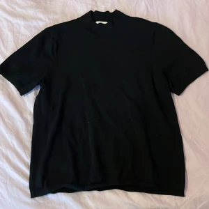 Stickad T-shirt - En svart stickad t-shirt med lite högre krage och lite längre ärmar, från H&M Basics i strl L. Basic men väldigt fin till ett par jeans eller vad som. 