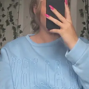 Blå sweatshirt i storlek M med tryck framtill 