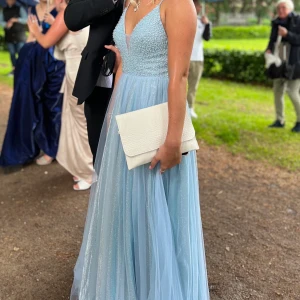 Balklänning - Ljusblå glittrig balklänning, en riktig dröm klänning! Köpt i stl 40 men är insydd till ca stl 38. Jag är ca 175. Köpt för 2500kr på Zalando, använd 1 gång. Pris kan diskuteras elr buda. Nyskick