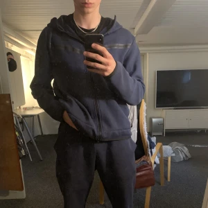 Nike Tech Fleece - Säljer min mörkblåa Nike tech fleece. Jag skulle säga att både tröjan och byxorna är i bra begagnat skick, byxan har dock ett hål i vänster ficka. Nypris på hela settet ligger på ungefär 2500 kr, skriv vid frågor. Köparen betalar frakt.
