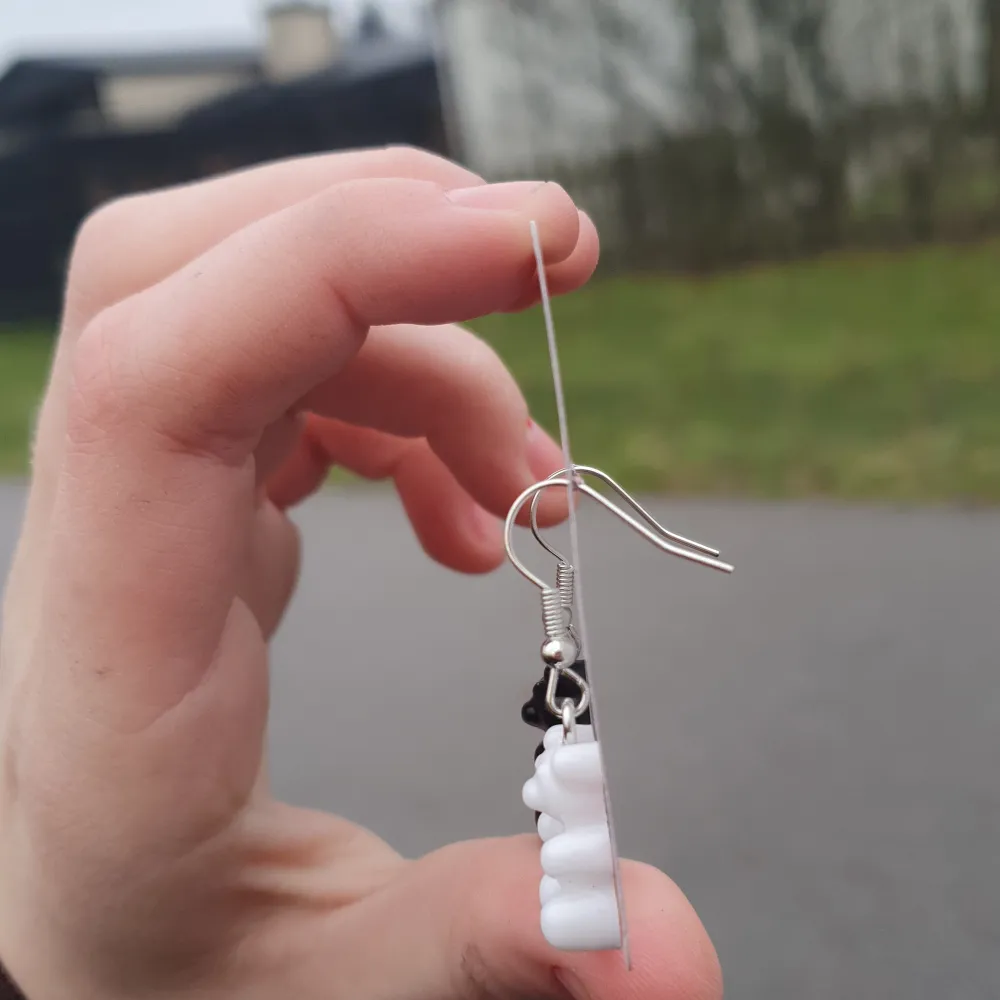 Gummibjörnar i hängande örhängen en svart en vit. Accessoarer.