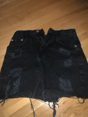 Jeans kjol - En svart jeans kjol från pull&bear, den har hål🖤väldigt fin kjol! Bra till sommaren! Inte mycket använd.🖤