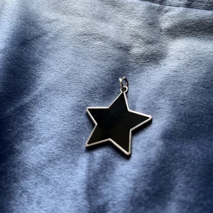 Berlock svart stjärna - Berlock till halsband med svart stjärna. Både fram och baksida är fina och går att använda utåt. Stjärnan är 3 cm lång. (Frakt går att fixa för 15kr)