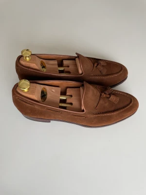 Tassel Loafers Meermin 45 - Fina tassel loafers i brun mocka. Tillverkade för hand i Spanien. Randsydd konstruktion gör det möjligt att byta ut hela sulan hos en skomakare vid behov. Bra skick! Nypris ca 2000 kr. 