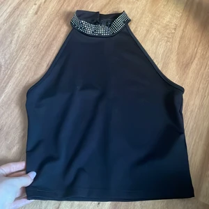 Svart topp - Fin svart topp med små pärlor som detaljer, knäppe runt halsen med två knappar. Tyvärr har några små pärlor ramlat av.