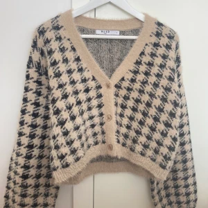 NA-KD Kofta - Nyskick. NA-KD Trend Rutig stickad kofta i storlek S/36-38. Den är en beige/svart kardigan, har en v-ringning, lång ärm och oversize fit med en mjuk känsla. Ej förbetalad frakt. Utgångspriset 529kr. 