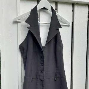 Unik byxdress - Unik svart byxdress med öppen rygg och snygg liksom skjortstil framtill. Benen är en aning vida nertill. Kan skicka mer bilder om önskas.