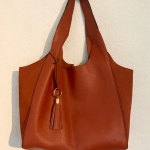 Väska - Säljer denna stora Axelväska i en perfekt burnt orange färg nu till hösten, den har ett stort fack där man får plats med de mesta.  Har några små fläckar (fråga för bild).