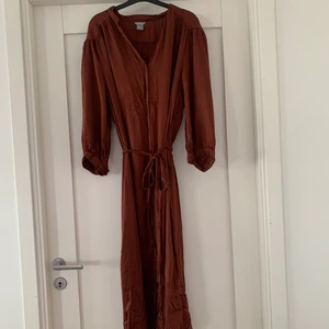 Klänning  - Fin klänning ifrån Lindex i ett glansigt material. Knyte i midjan. 