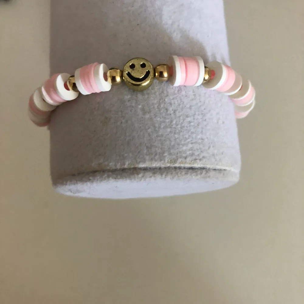 Rosa armband med guldsmiley och rosa blommor  15kr plus 12kr frakt  Mät din vrist för att veta din storlek  Instagram: smileyyjewelry 💗🤍. Accessoarer.