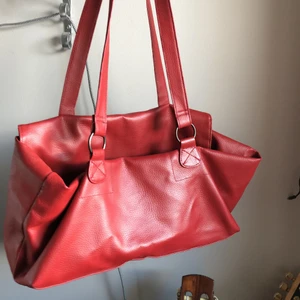 Väska - Röd väska i skinn imitation. Köpt i Frankrike. Lite konstig att stänga men man lägger ”locket” i väskan. 