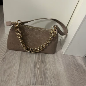 Beige väska  - Denna väska är ifrån New Yorker och har gulddetaljer. Kedjan är avtagbar som ni ser på bilderna. Säljer denna för 80kr!
