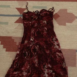 Super fin vinröd klänning med coolt mönster - Snygg klänning i längd till ovanför knäna. Fin knut fram