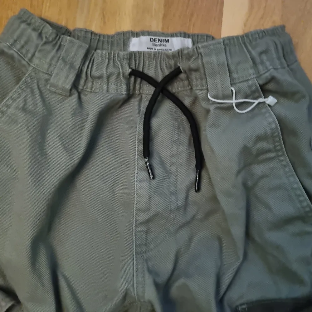 Gröna Cargobyxor med fickor av olika färger. Midja: 73 cm (flexibel), Längd: 90 cm. Jeans & Byxor.