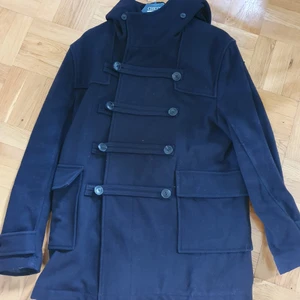 Snygg svart Jacka med Luva J.Lindeberg - Jacka med luva och knäppning. Har ett par år på nacken men inte använts senaste 4åren och bara hängt i garderoben. Helt ok skick, Kostade 4000kr ny