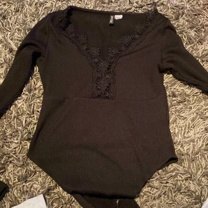 Svart body H&M strl S - Aldrig använd body från H&M, jättefin med ett fint mönster vid bysten. Storlek S men passar även xs 
