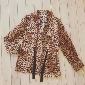 Skjortjacka i leo  - Såå härlig tunnare jacka med knappar fram, fickor fram och band i midjan. Storlek 34, men passar mig bra som vanligtvis har 36/S. Från other stories. Använd fåtal ggr, nyskick. 