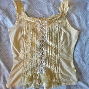 Gul korsettliknande top  - Fint linne med många detaljer. Står L men skulle säga att M passar bättre. Dragkedja längst sidan. DMa för fler bilder eller mått. Köpare står för frakt