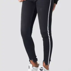 Svarta jeans med vit/grå rand på sidan av benen. Aldrig använda!