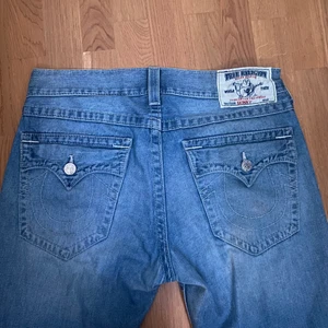 Baggy True Religion jeans med snygga fickor - Trueys med hästskofickor, köpta på stöldvintage för 1200. Byxorna är endast använda 2-3 gånger och sitter perfekt på mig(Baggy) är 180 lång och brukar ha 32-34. Waisten är 32 och längden är 34. Byxorna är i väldigt gott skick och har en fin ljusblå fade.