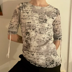 Grå vit svart meshtröja trekvart ruche  - Grå och vit trekvartsärmad tröja i mesh med tryck av svart text och lettucehem köpt på second hand 🤍🤍 Älskar att ärmarna har justerbara band som gör att man antingen kan ha de långa eller kortare och ruched!