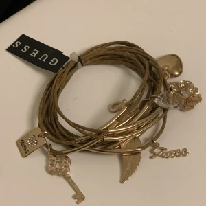 Guess armband  - Oanvänd guess armband med massor med berlocker. 