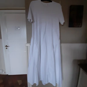 COS lång klänning - Klänning från COS i bomull med fina assymetriska detaljer. Jerseybomull i livet och kraftigare bomull i kjolen. Märkt 38, men COS storlekar stämmer inte med svenska storlekar, så strl 40.