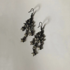 Vita strass örhängen  - Örhängen i mörkare metall med kritvita stenar. Dm:a gärna vid frågor eller funderingar! Köparen står för frakt.
