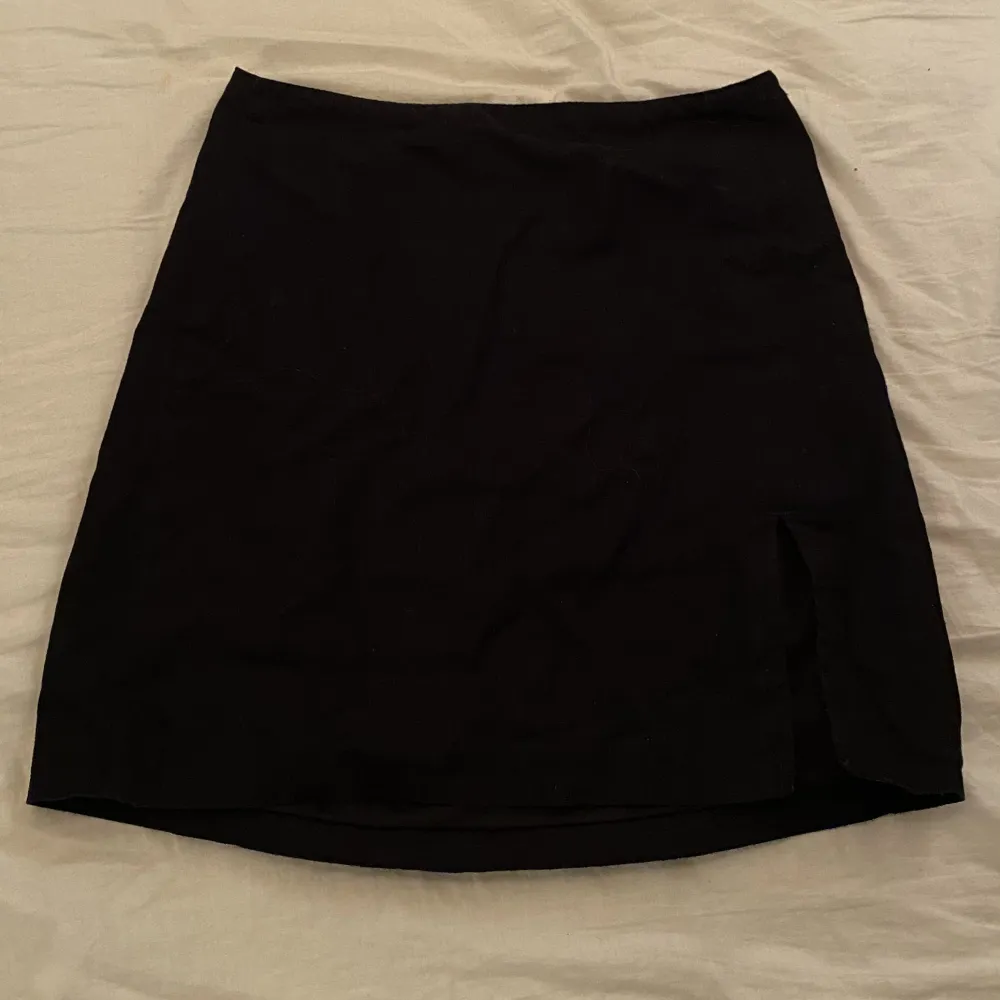 Svart kjol med en liten slits på ena benet från H&M i storlek 32. Kjolar.