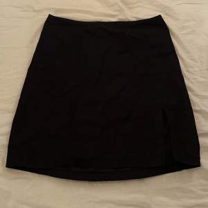 Svart kjol med en liten slits på ena benet från H&M i storlek 32