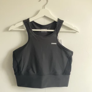 Stronger träningstopp storlek M - Svart träningstopp från Stronger storlek medium, sitter tight mot kroppen. Säljs pga. att storleken inte passar. Helt oanvänd, lappen sitter kvar i toppen och har skicket som en helt ny. Köpt för 399kr.
